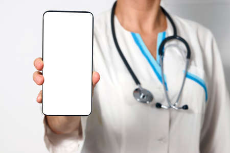 Woman Doctor with smartphone. Female doctor with mobile phone. Nurse holding her cellphone in handの写真素材