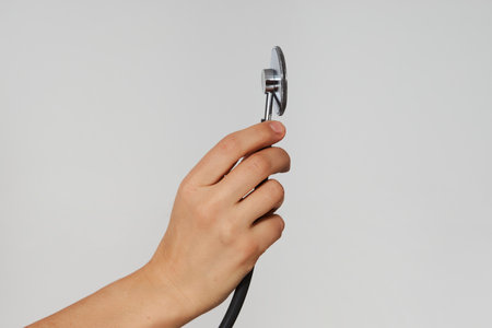 Hand with stethoscope on white background with copy space, close-up. Healthcare and medicine conceptの写真素材