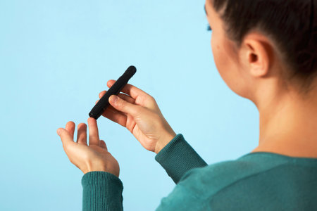 Woman using lancet pen. Young woman testing her blood sugar level. Diabetes and Coronavirus...
