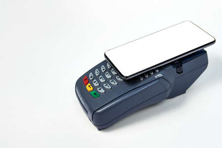 Payment terminal and phone on white background with copy space, close-up. Contactless payment...