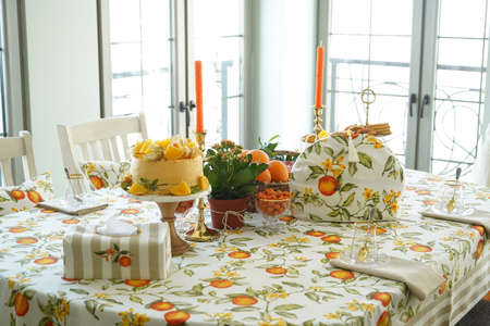 Table with orange cookies, fruits snacks. Table setting with tablecloth  and food