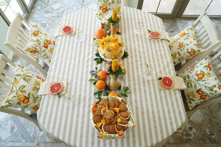 Table with orange cookies, fruits snacks. Table setting with tablecloth  and food