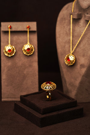 Women jewelry on brown background. Golden jewellery set with earrings, ring and necklace with pendant, close-up, selective focusの写真素材