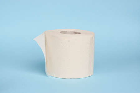 White toilet paper roll on blue background with copy space, close-up
