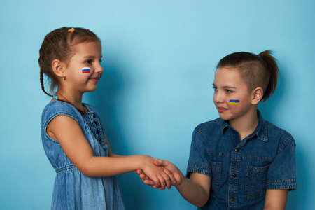 Friends boy and girl with flags of Ukraine and Russia painted on face. Peace friendship, conflict and stop war.の写真素材