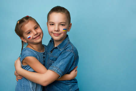Friends boy and girl with flags of Ukraine and Russia painted on face. Peace friendship, conflict and stop war.の写真素材