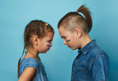 Friends boy and girl with flags of Ukraine and Russia painted on face. Peace friendship, conflict and stop war.の写真素材