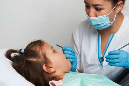 Girl visiting dentist. Little girl with open mouth sitting in the dentist's chair, close-upの写真素材