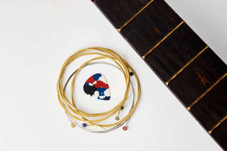 Acoustic guitar strings and pick on white background, close-up