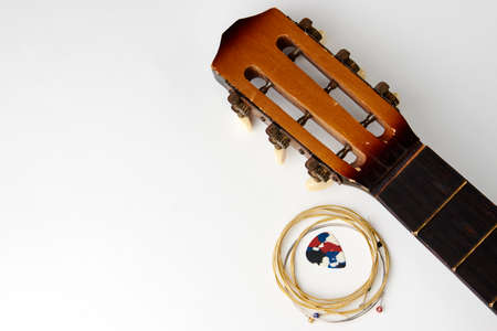Acoustic guitar strings and pick on white background, close-up