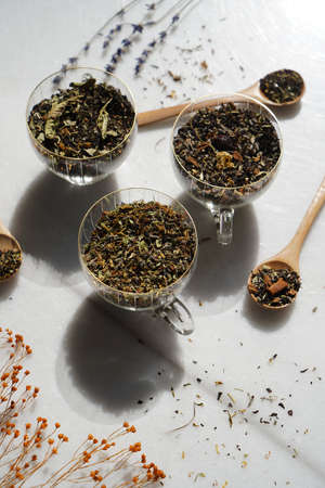 Dried tea cups with a tea spoon and green leaves. Variety of tea leaves