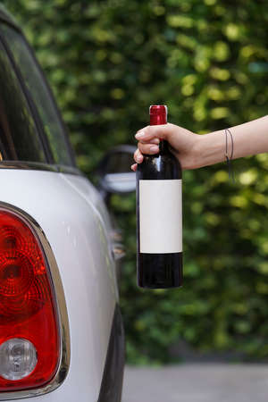Hand holding bottle of wine, close-up. Woman's hand with wine bottle