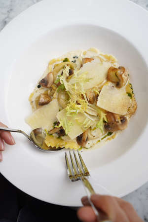 Farfalle pasta with mushroom, cheese and sauce. Traditional Italian Farfalle pasta in a white plate on a table, close-up.の写真素材