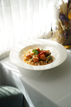 Tagliatelle pasta with salmon, baked tomato and parmesan cheese. Traditional Italian Tagliatelle pasta in a white bowlの写真素材