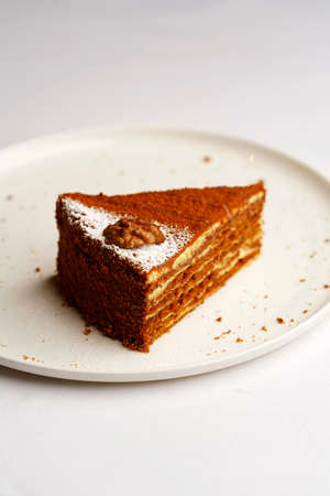 Piece of honey cake on a white plate, close-up