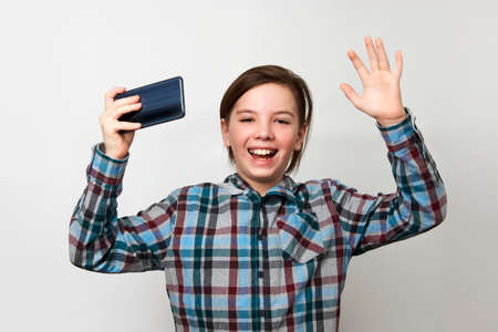 Boy using smartphone on a white background with copy space. Portrait of young boy holding mobile...