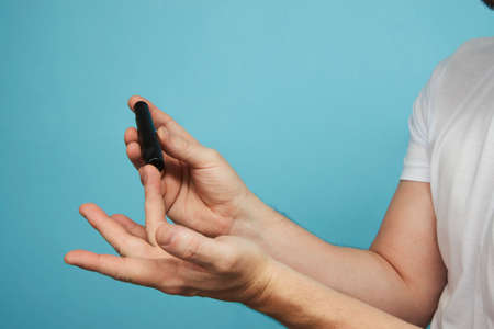Man with lancet pen doing diabetes test, close-up. Finger blood glucose sample, Check diabetes conceptの写真素材