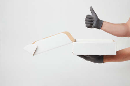 Hand holding cardboard box on over white background with copy space. Delivery and shipping service...