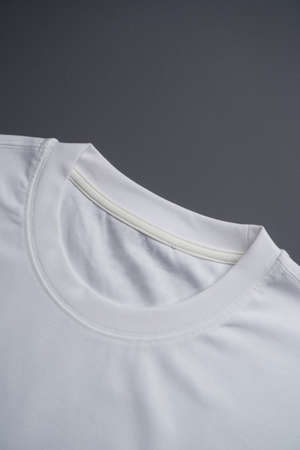 Blank white t shirt, top view. Folded t-shirt on a gray background