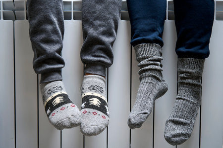 Warming feet on heater, close-up. Woman warming her Feet on white radiator, close-upの写真素材