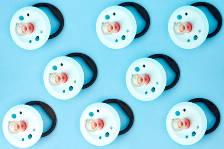 Baby pacifier on a blue background, close-up. Rubber pacifier pattern, top view