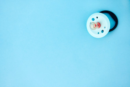 Baby pacifier on a blue background with copy space.