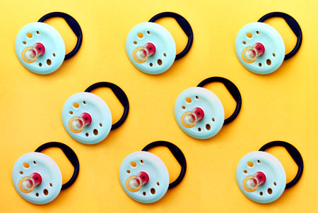Baby pacifier on a yellow background, close-up. Rubber pacifier pattern, top viewの写真素材