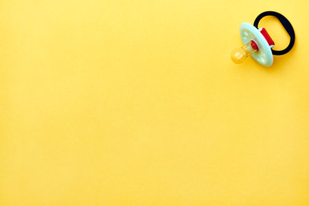Baby pacifier on a yellow background with copy space. Rubber pacifier, top viewの写真素材