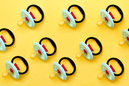 Baby pacifier on a yellow background, close-up. Rubber pacifier pattern, top view