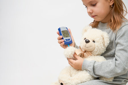 Children and diabetes concept with little girl checking diabetes test to toy bear.の写真素材