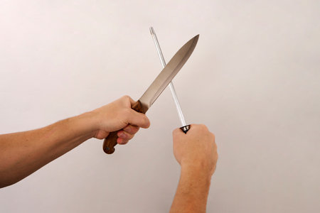 Chef cook holding kitchen knives on white background with copy space, close-up portrait