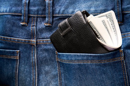 Black leather wallet in jeans back pocket. Money wallet in a pocket, close-up