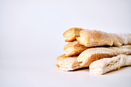 Puff pastry sticks with cinnamon on white background with copy space. Breadsticks sprinkled with sugar, close-upの写真素材