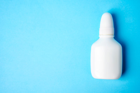 Nasal spray bottle on blue background with copy space. White plastic medical spray bottle, close-upの写真素材