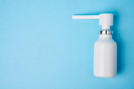 Nasal spray bottle on blue background with copy space. White plastic medical spray bottle, close-upの写真素材