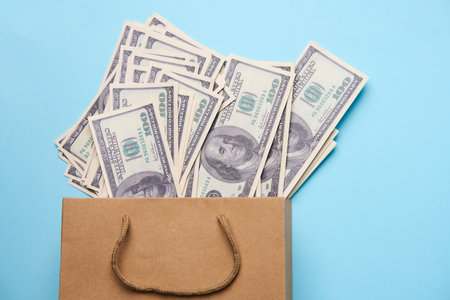 Paper money bag with dollar bills. US dollar currency on blue background with copy space, close-upの写真素材