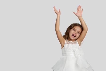 Portrait of a cute smiling girl wearing white dress, close-up. Happy child girl on white background with copy spaceの写真素材