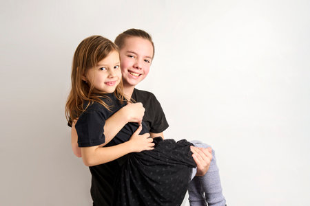 Brother and sister kids having fun. Portrait of teenage boy and preschool girl playing together on white backgroundの写真素材