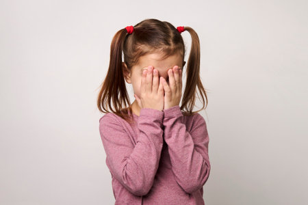 Baby girl covering eyes with hands. Little girl covering her face, see no evil, white backgroundの写真素材
