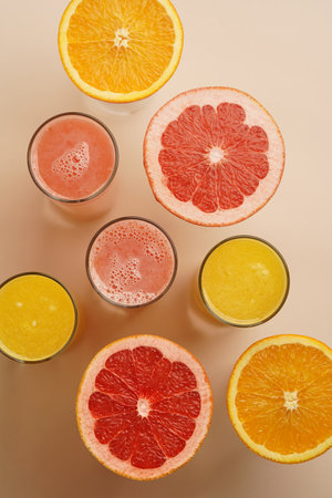 Glasses of citrus juice with sliced fruits on pastel background with copy spaceの写真素材