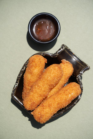 Chicken strips nuggets and sauce on a black plate, background with copy space, close-upの写真素材