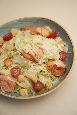 Traditional caesar salad with shrimp and chicken in a vintage bowl with lettuce leaves and a sauce boat and parmesanの写真素材