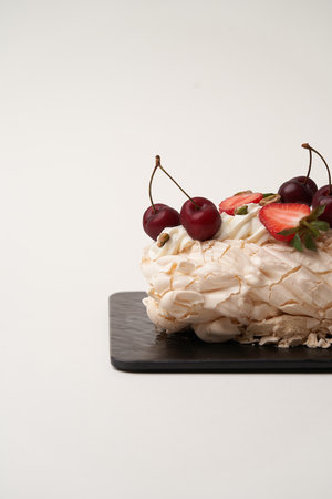 Meringue roll cake with strawberry and cherry. Pavlova roll cake with fresh berries on white backgroundの写真素材