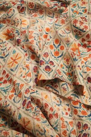 Orange cotton textile background. Folded linen fabric with flowers ornament texture