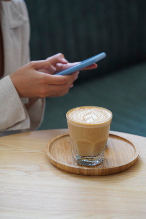Woman hand holding coffee cup. Woman sitting at table and drinking coffee, close-upの写真素材