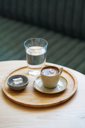 Coffee cup and glass of water on wooden tray, light background with copy space, close-upの写真素材
