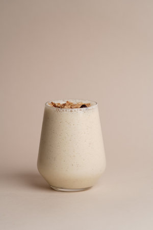 Glass of milkshake smoothie with cereal flakes on light background with copy space, close-up. Healthy breakfastの写真素材