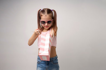 Cute little girl with shopping bags on a white background with copy space. Portrait of a child girl with colorful shopping bags, full bodyの写真素材