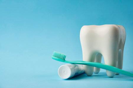 Toothbrush with toothpaste and white tooth on a blue background with copy space. Oral hygiene, teeth cleaning. Dental careの写真素材