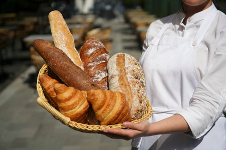 Baker female hands holding basket with fresh bread and croissant. Bakery and fresh pastry shop